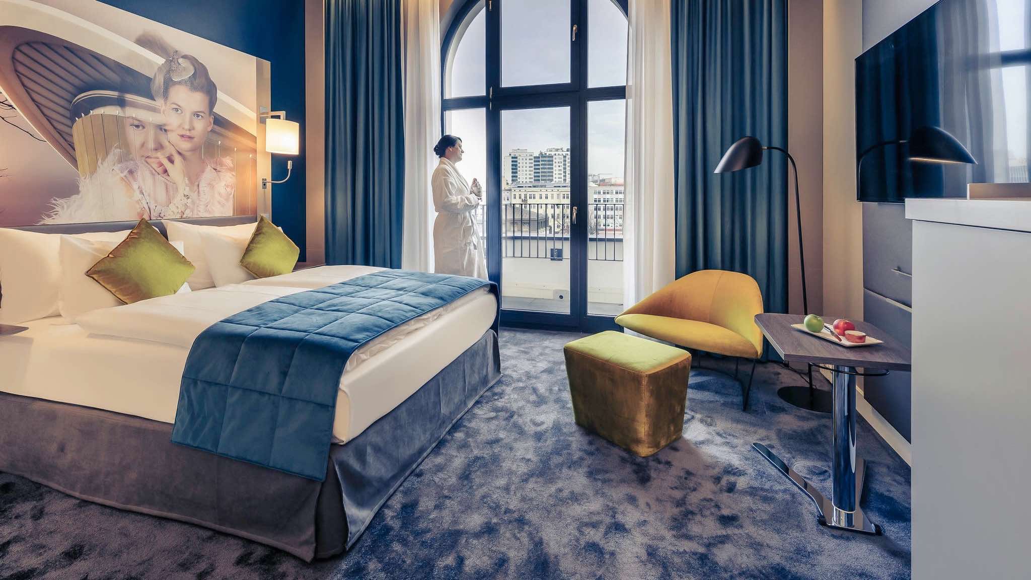 Mercure Hotel Berlin Wittenbergplatz luxury design hotel in Berlin with woman standing at window in bathrobe